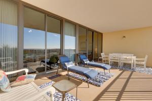 a room with chairs and tables on a balcony at Oceanfront Resort Condo with Private Beachwalk! in Dauphin Island