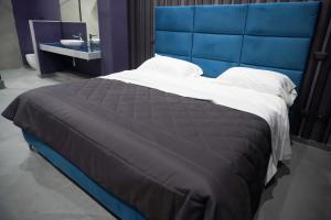 een groot bed met een blauw hoofdeinde in een kamer bij Hotel El Pamas in Mugnano di Napoli