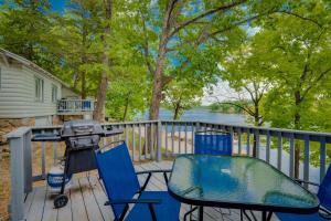a grill and chairs on the deck of a house at Lakeshore Cabin 2 dock, boat slip and patio in Lake Ozark