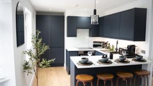 a kitchen with black and white cabinets and stools at Oakleigh House, 3 bedroom, free parking in East Barnet
