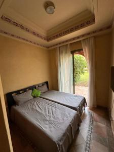 Ce lit se trouve dans un dortoir doté d'une fenêtre et d'une sidx. dans l'établissement Les Jardins de la Palmeraie II, à Marrakech