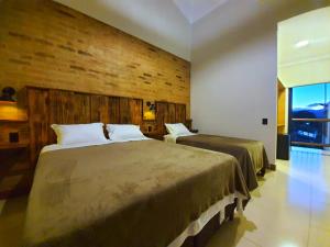 1 dormitorio con 2 camas y pared de madera en Suítes Capitólio Canastra en Capitólio