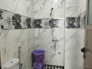 y baño con ducha y paredes de mármol blanco. en Appartement Hajar, en Oualidia