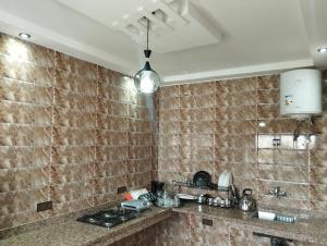 a kitchen with brown tiled walls and a counter top at Appartement Hajar in Oualidia