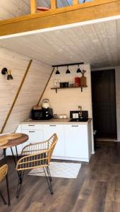 cocina con armarios blancos, mesa y sillas en Haus im Wald, en Lindig