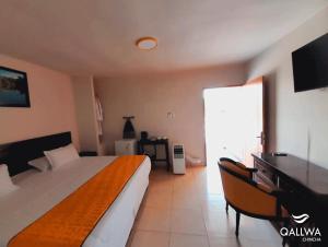 a bedroom with a bed and a desk and a television at Qallwa Chincha in Chincha Alta