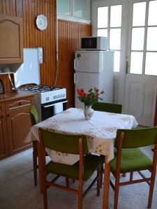 eine Küche mit einem Tisch und einem weißen Kühlschrank in der Unterkunft Madácsi Vendégház in Kiskőrös