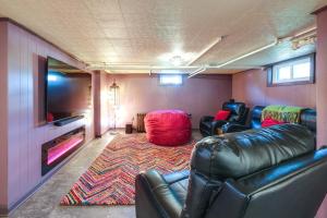 a living room with leather furniture and a flat screen tv at Colorful Roanoke Vacation Rental with Hot Tub! in Roanoke