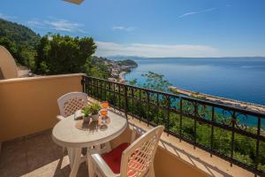 a balcony with a table and chairs and a view of the water at Apartments Gudelj in Podgora