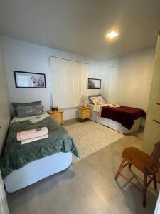 una habitación de hotel con dos camas y una silla en Casa Floratta, en Santa Cruz do Sul 16 fotos más