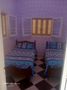 2 camas en una habitación con paredes y ventanas moradas en الوحيد للإستثمار العقارى برأس البر, en ‘Izbat al Burj