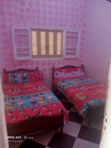 2 camas en una habitación con paredes rosas en الوحيد للإستثمار العقارى برأس البر, en ‘Izbat al Burj