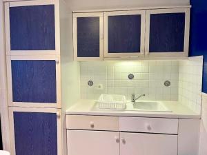 una cocina con armarios blancos y fregadero en Entre Paris et Disneyland Studio avec terrasse privée, en Gagny