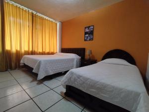 HOTEL PUERTA DEL SOL في سانتو دومينغو دا لوس كولورادوس: غرفة فندقية بسريرين ونافذة