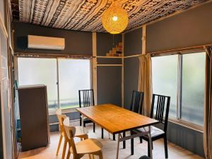 温泉街の入り口にあるゲストハウス SLOW HOUSE yugawara في يوغاوارا: غرفة طعام مع طاولة وكراسي خشبية