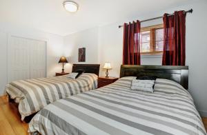 two beds in a bedroom with red curtains at Chalets Alpins- 39 Chemin des Skieurs in Stoneham