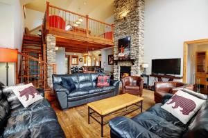 a living room with leather furniture and a staircase at Chalets Alpins- 39 Chemin des Skieurs in Stoneham