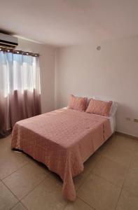 Schlafzimmer mit einem Bett mit rosa Bettwäsche und einem Fenster in der Unterkunft Apto Pampatar - Isla de Margarita in Pampatar