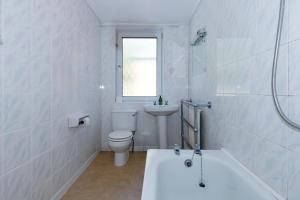 Baño blanco con aseo y lavamanos en Phoenix Rise Retreat, en Glastonbury