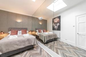 a bedroom with two beds and a mirror at The Secret KENSINGTON Garden Mews-2 Bedroom FULL HOUSE-2 Train Lines- SPACIOUS-Kings Road- Harrods -Chelsea Stadium-PRIVATE small patio in London