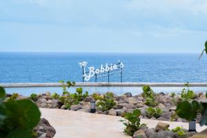 una señal en las rocas cerca del océano en Golden Rock Dive and Nature Resort en Oranjestad