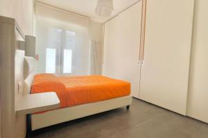 un letto arancione in una camera bianca con finestra di Appartamento Letizia a Prato