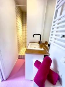 La salle de bains est pourvue d'un lavabo et d'un tabouret pourpre. dans l'établissement Ruby- Quai St Laurent- Bastille, à Grenoble