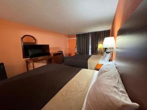 a hotel room with two beds and a flat screen tv at College Inn Spartanburg in Spartanburg