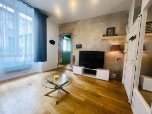 un salon avec une télévision et une table en verre dans l'établissement Ruby- Quai St Laurent- Bastille, à Grenoble