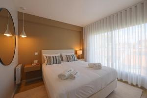 een slaapkamer met een wit bed en 2 handdoeken bij FLH Boavista Woody Duplexes in Porto