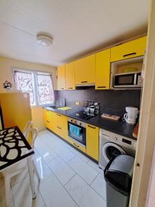 uma pequena cozinha com armários amarelos e uma mesa em l'ESCALE à 50 m de la gare em Viry-Châtillon