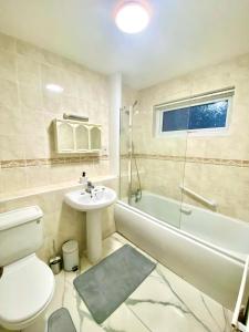 a bathroom with a toilet and a sink and a tub at Luxury Large Four Bedroom Family House in Luton