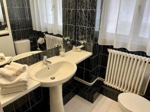 a black tiled bathroom with a sink and a toilet at Cosy apartment proche Paris et Disneyland in Gagny +25 photos