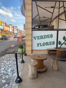 Pousada Verdes Flores في برازيليا: يوجد علامة على متجر فيردس فلوريس مع مقاعد خشبية