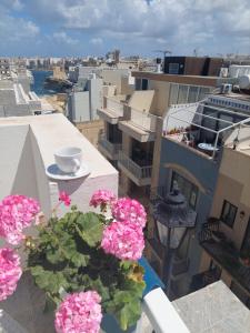 eine Vase mit Blumen auf einem Balkon mit rosa Blumen in der Unterkunft MB SEA VIEW Apartment in St Paul's Bay