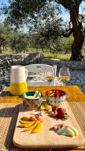 a table with fruits and vegetables on a table with wine glasses at Villa Colle dei Trulli Monopoli in Monopoli