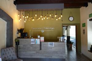 un restaurant avec une horloge sur le mur et des lustres dans l'établissement Hotel La Merced, à Colima