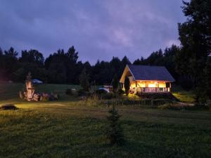 una casa con luces encendidas en un campo por la noche en Üleoja Saunamaja, 