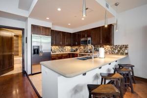 una cocina con armarios de madera y una gran isla con taburetes. en Sprawling Condo - Central Downtown - Summer AC, en Steamboat Springs
