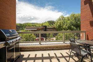 a balcony with a grill and a table and chairs at Sprawling Condo - Central Downtown - Resort 10-min in Steamboat Springs
