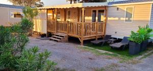 a wooden cabin with two chairs and a porch at Mobil-home Le cocon in Canet-en-Roussillon