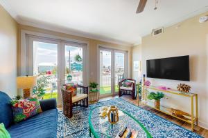 Una sala de estar con un sofá azul y un televisor de pantalla plana. en Tranquil Harbour 103: Casa Del Mar, en Mexico Beach