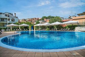 ein großer blauer Pool mit Sonnenschirmen und Stühlen in der Unterkunft Hotel La Giocca in Rom