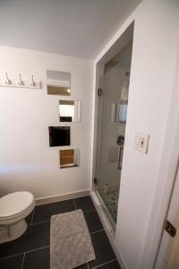 ein weißes Bad mit einem WC und einer Dusche in der Unterkunft 2 Bedroom by Zoo, Metro, Park and Embassies in Forest Hills - Best Location in Washington