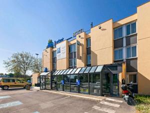 a building with a motorcycle parked in a parking lot at ibis budget Antony Massy rénové 2024 in Antony