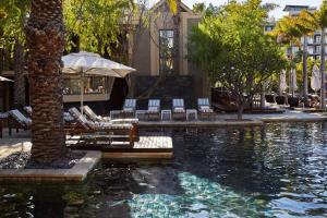 a pool of water with chairs and an umbrella at One&Only Cape Town in Cape Town