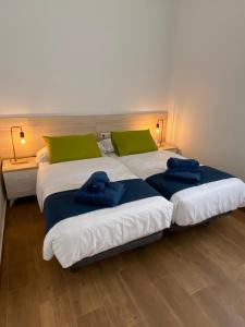 two beds in a room with two blue towels on them at Apartament centre casaPat in Xàtiva
