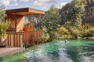 a person swimming in a swimming pool with a house at One&Only Gorilla's Nest in Kinigi