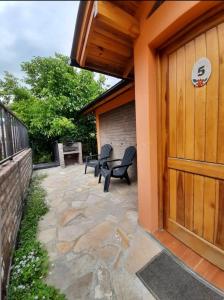 a patio with two chairs and a wooden door at Cabañas Bosque Andino con hidromasaje in Esquel