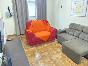 - un salon avec une chaise rouge et un canapé dans l'établissement Pé na areia praia da Guilhermina II, à Praia Grande